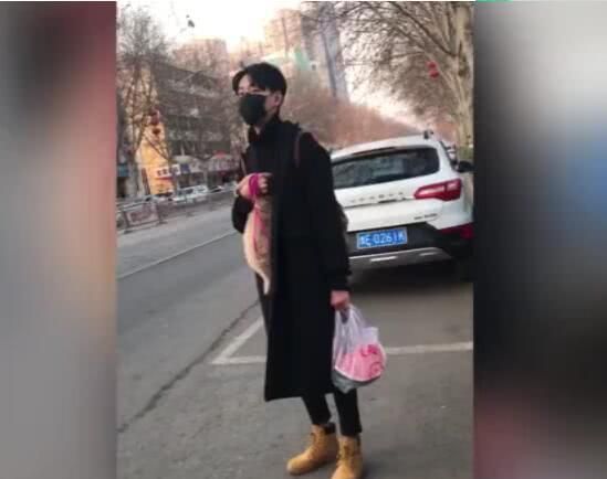 小伙把狗狗抱怀里，手捂住狗狗的头，捂到狗无精打采！