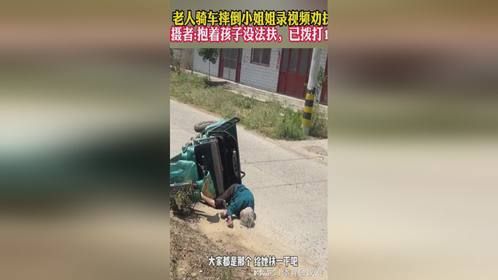 老人骑车摔倒 小姐姐录视频劝扶