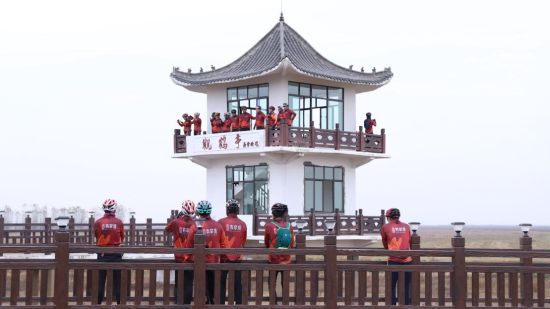 图为骑行爱好者在观鸟亭观看候鸟