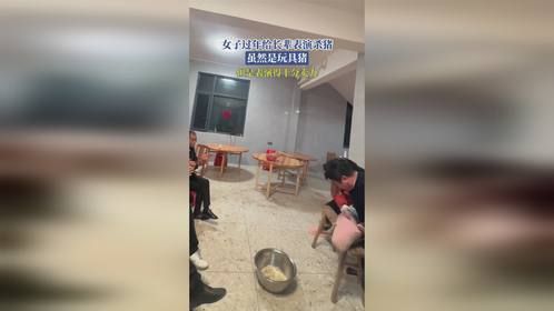 女子过年给长辈表演杀猪，虽然是玩具猪，但是表演得十分卖力