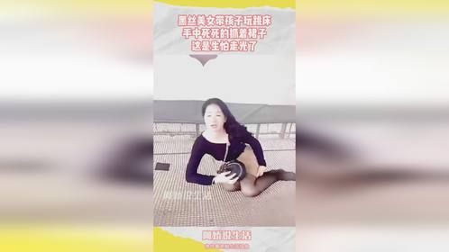 黑丝美女带孩子玩蹦床，手中死死的抓着裙子，这是生怕走光了