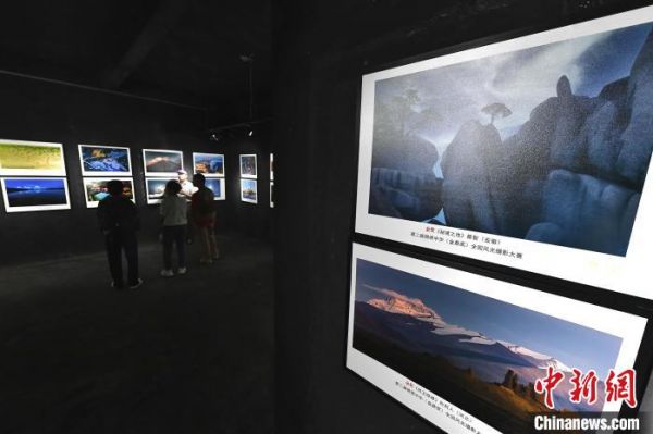 图为摄影爱好者在观看展出的摄影作品。　张斌 摄