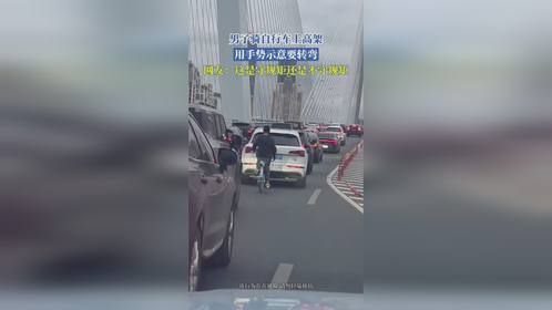 男子骑自行车上高架，用手势示意要转弯，网友：这是守规矩还是不守规矩