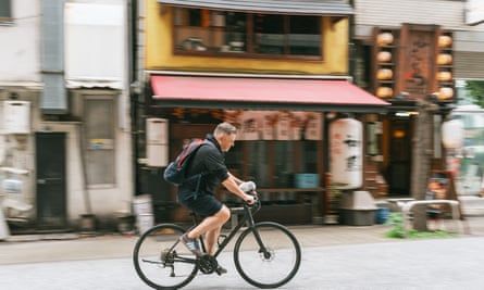 Hammy sitting on Justin McCurryâ€™s handlebars as they cycle through the Tokyo streets