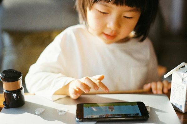 穿着白色长袖衬衫、拿着黑色智能手机的女人