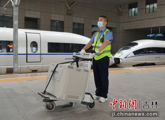 工作人员携带装有宠物猫的运输箱在站台等候