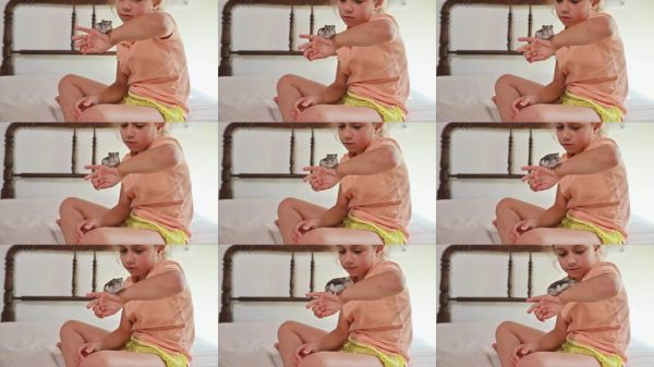 年轻女孩坐在床上,轻柔地将一只小宠物仓鼠抱在手臂上,展现出与家庭宠物之间的亲密互动。