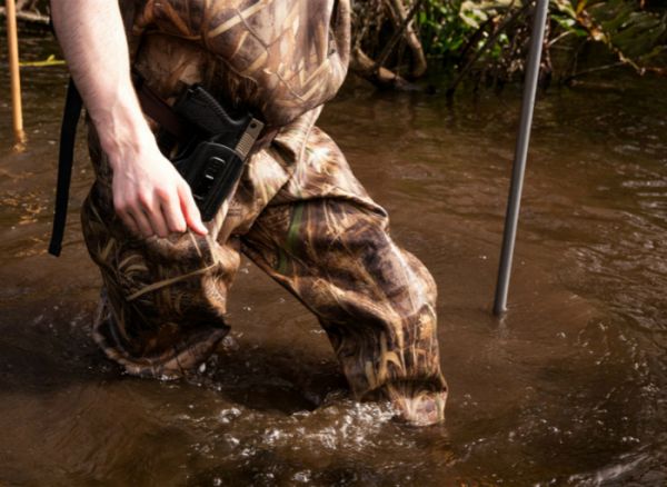 一名猎手在河堤边缘涉水行走